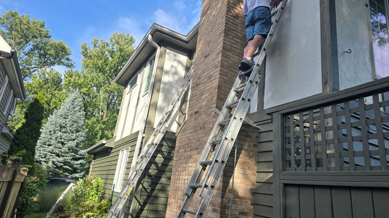 Person on ladder painting the side of a house.