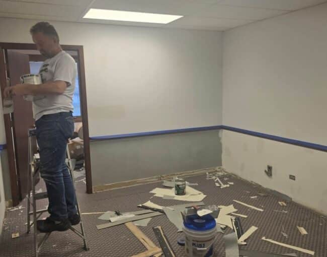 A person is painting a room that is undergoing renovation.