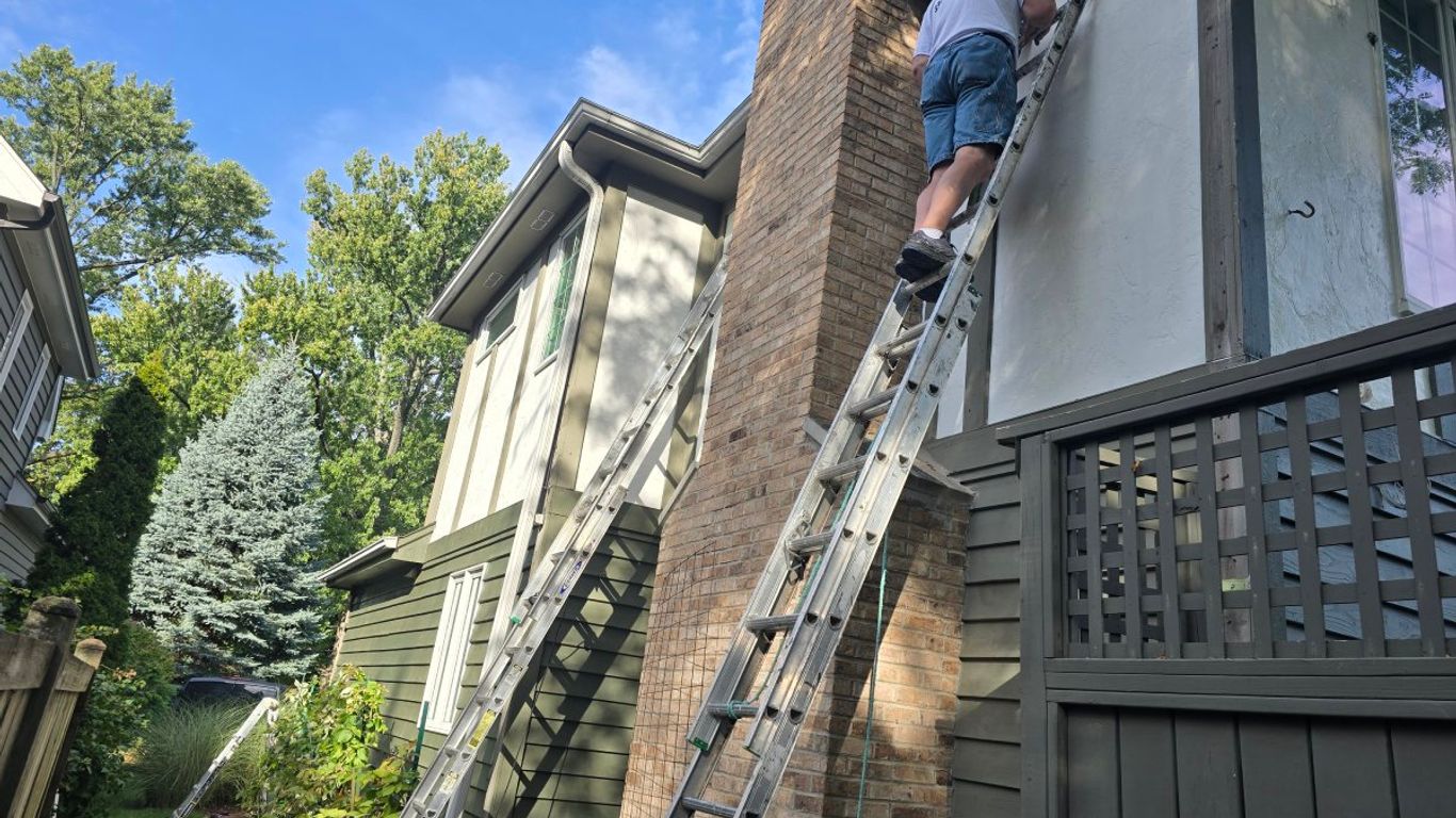 Person on ladder painting the side of a house.