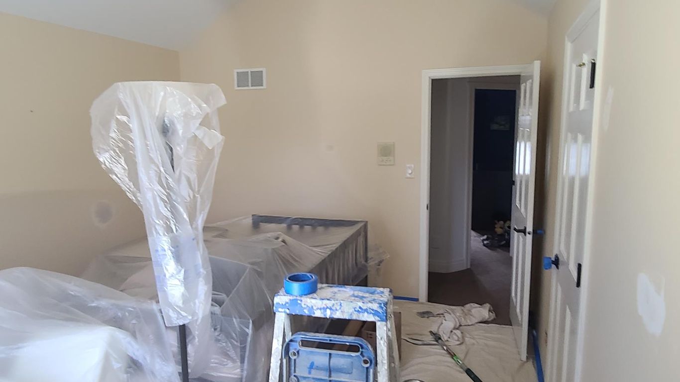Room being painted with furniture covered in plastic.