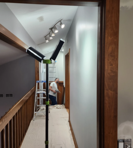 Professional painter working on a high ceiling project with safety equipment.