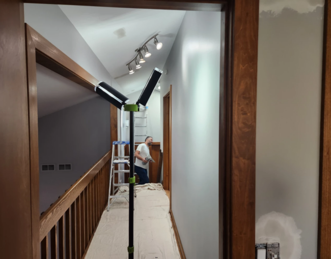 Professional painter working on a high ceiling project with safety equipment.