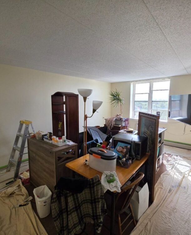 Living room walls being painted in an Elmwood Park, IL apartment, with floors covered and baseboard heaters taped off
