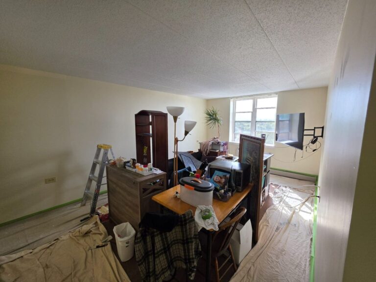 Living room walls being painted in an Elmwood Park, IL apartment, with floors covered and baseboard heaters taped off