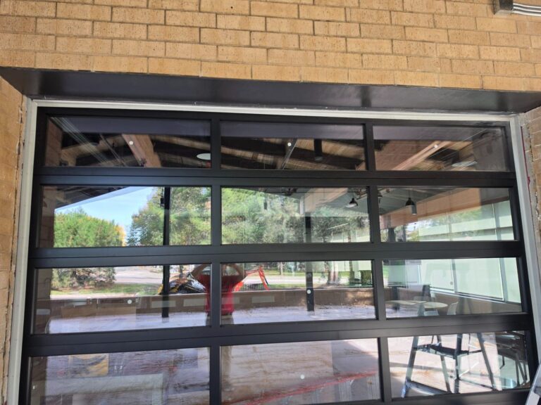 Metal header above a glass overhead door painted black to match the frame at a commercial building in Elmwood Park, IL