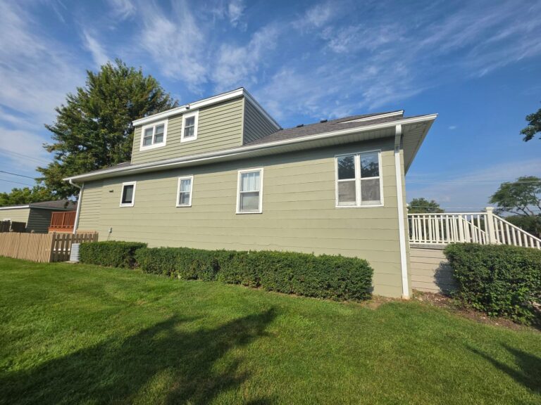 Side of a house with freshly painted sage green siding and white window trim in Hanover Park, IL