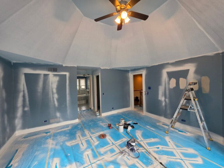 Bedroom with a vaulted ceiling being painted in Lemont, IL, with spot-primed walls and floors covered in protective plastic