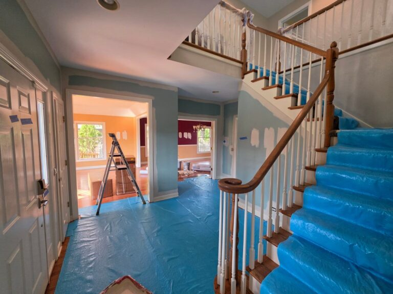 Two-story foyer with spot-primed walls and a staircase covered for protection during interior painting in Lemont, IL