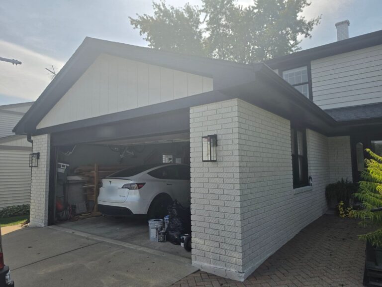 Garage with white-painted brick, white gable siding and black fascia and trim in Wheaton, IL
